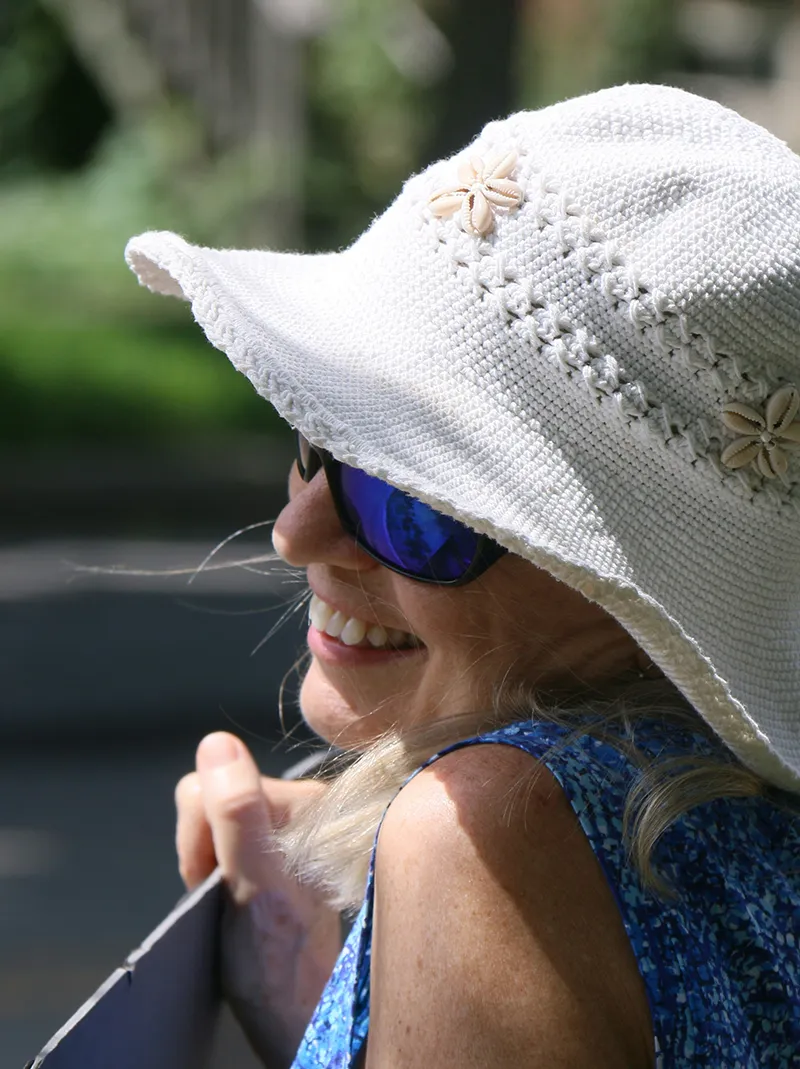 Smiling mature woman wearing a white sun hat and sunglasses outdoors